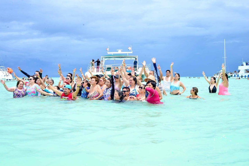 A group of people in the ocean with a boat in the background. 1