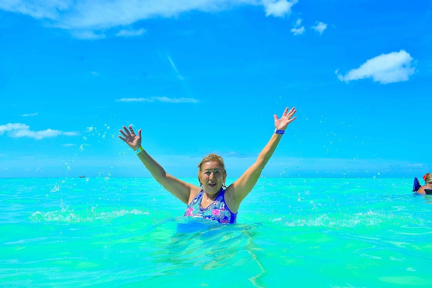 A person in a blue swimsuit with arms raised in the ocean. 3