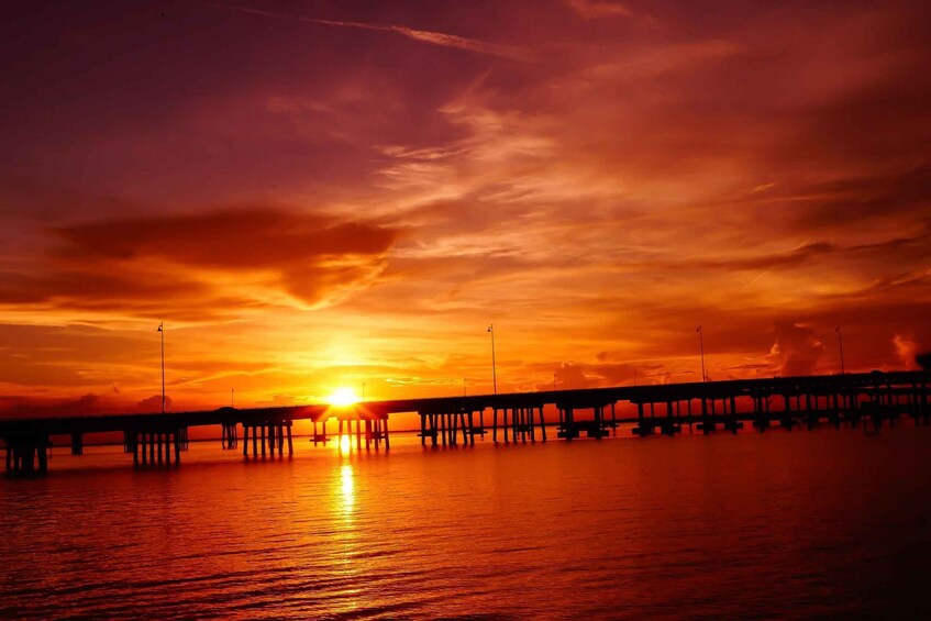 A sunset over a pier with the sun setting on the horizon. 2
