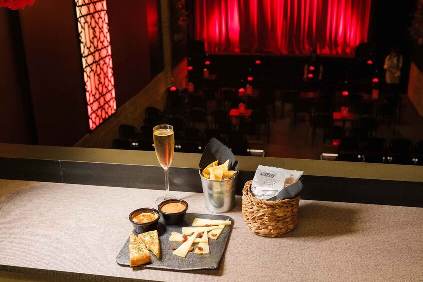 A table with cheese, crackers, a glass of wine, and a basket of bread. 3