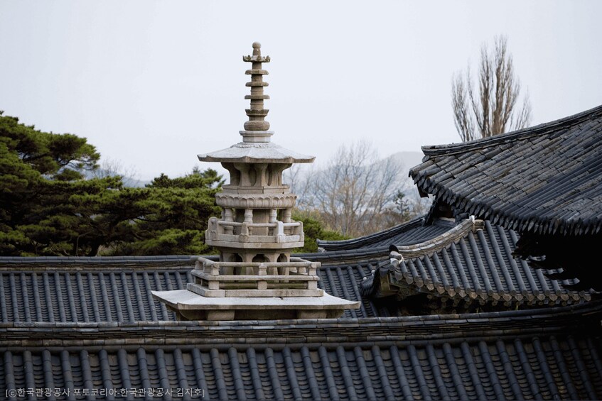 A traditional Korean pagoda with tiered roofs and a stone pagoda in the background. 2