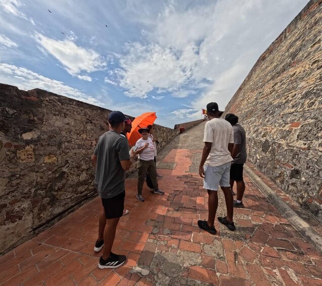 A group of people standing on a brick pathway between stone walls. 5