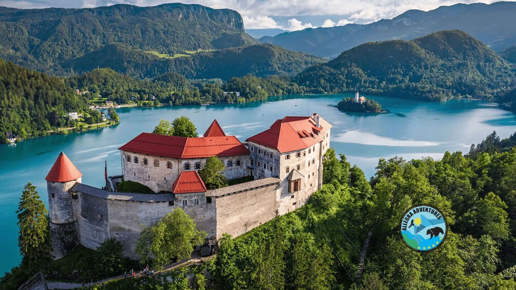 Un château entouré d’un lac et de montagnes boisées. 1