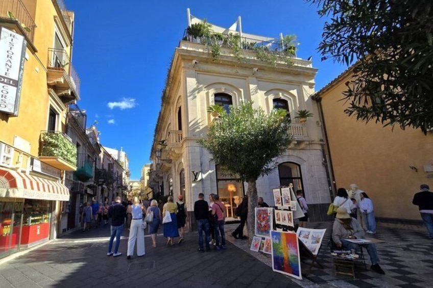 A street with people walking, a tree, and buildings with signs. 4