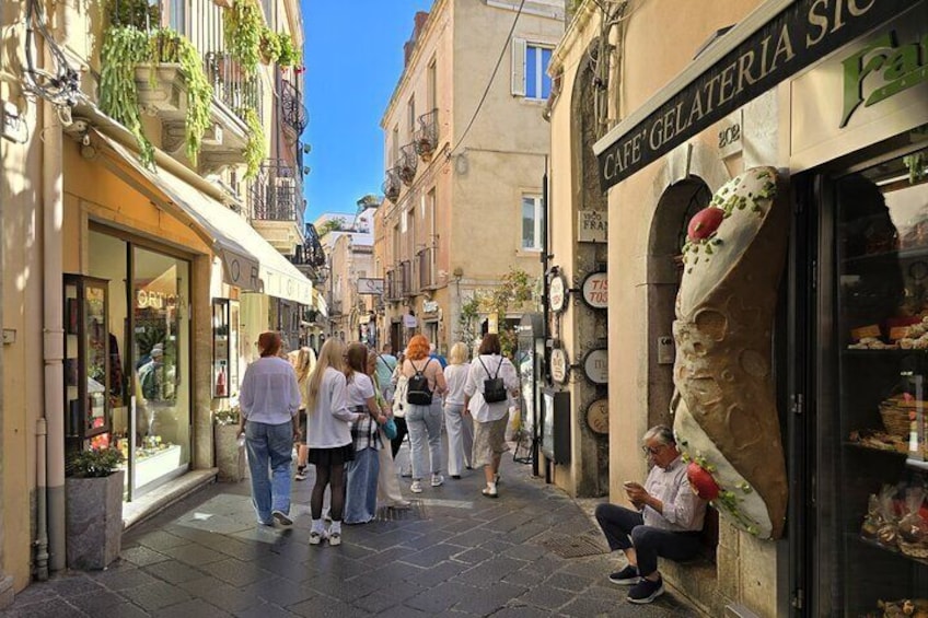 A narrow street with people walking and sitting. 2