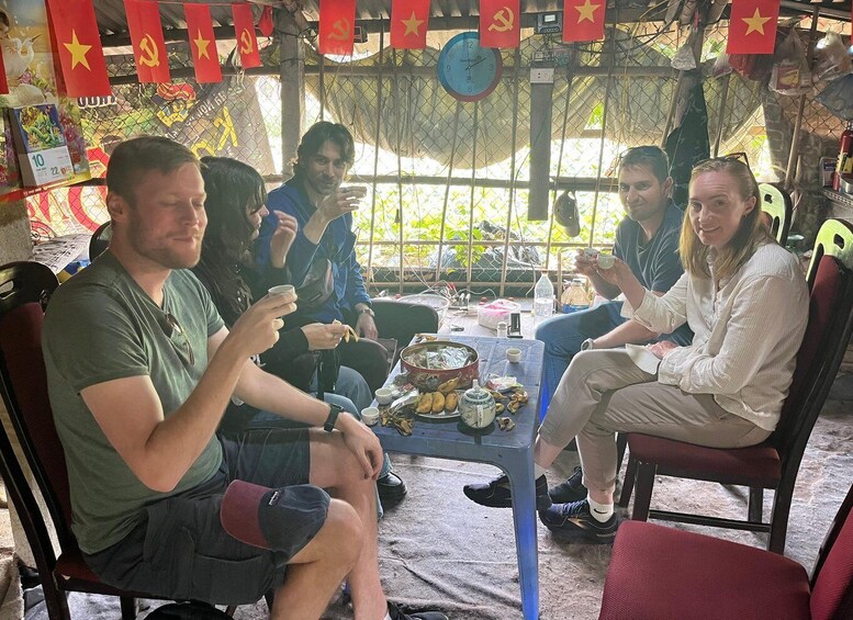 A group of people sitting at a table with food and drinks, surrounded by flags and a clock. 2