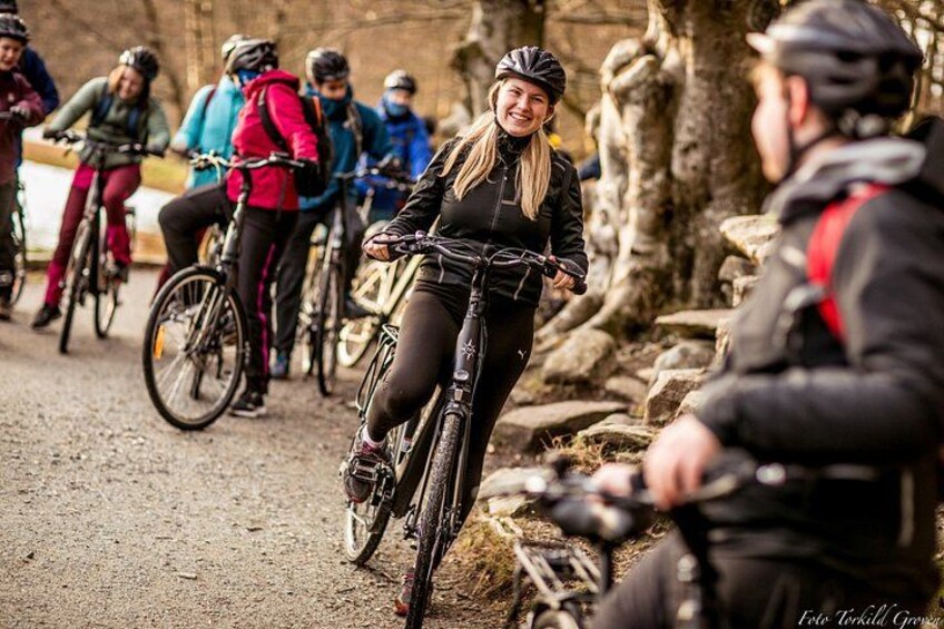 A group of cyclists on a dirt path with trees and rocks in the background. 1