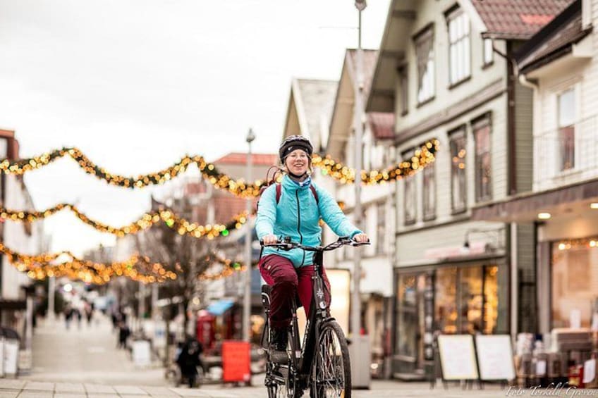 A person riding a bicycle on a street decorated with lights. 2