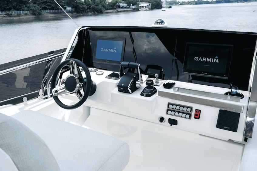 A boat's control station with a Garmin navigation screen, steering wheel, and various control buttons. 5