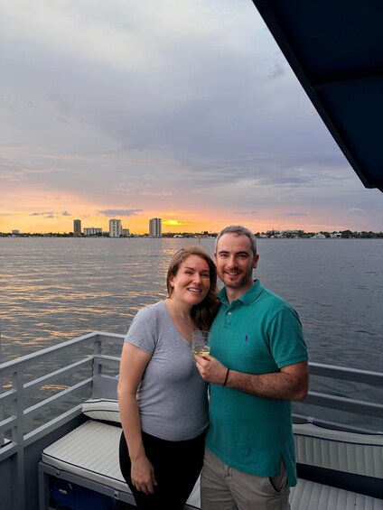 A couple on a boat with a city skyline and sunset in the background. 3