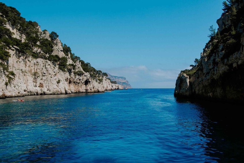 A coastal scene with clear blue water, rocky cliffs, and a distant mountain range. 1