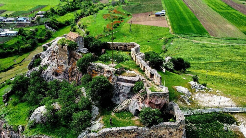 An aerial view of a historical stone fortress surrounded by lush green fields and a small village. 4