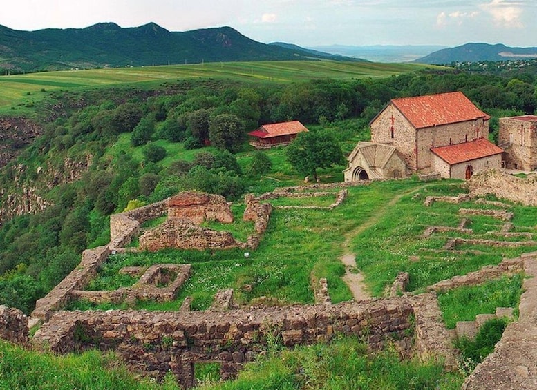 Ancient ruins and a stone church in a lush valley. 1