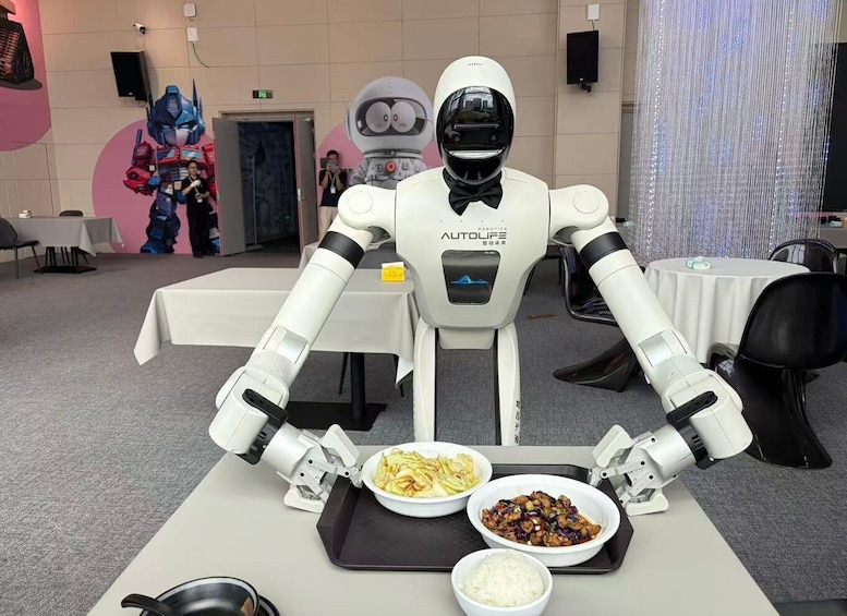 A robot serving food at a table in a room with a robot costume in the background. 1