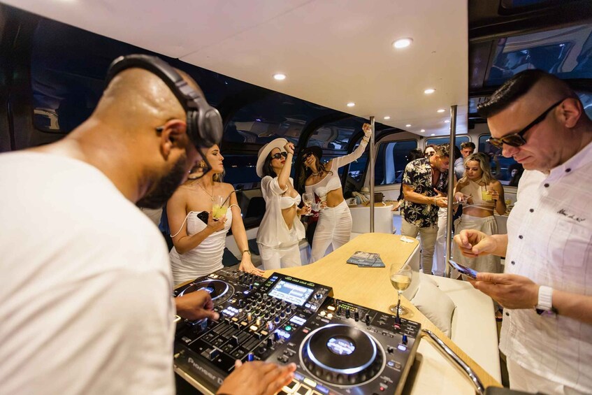 A DJ booth with a DJ and a crowd of people dancing. 1