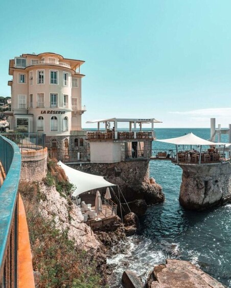 A coastal building named "LA RESERVE" with outdoor seating overlooking the sea. 5