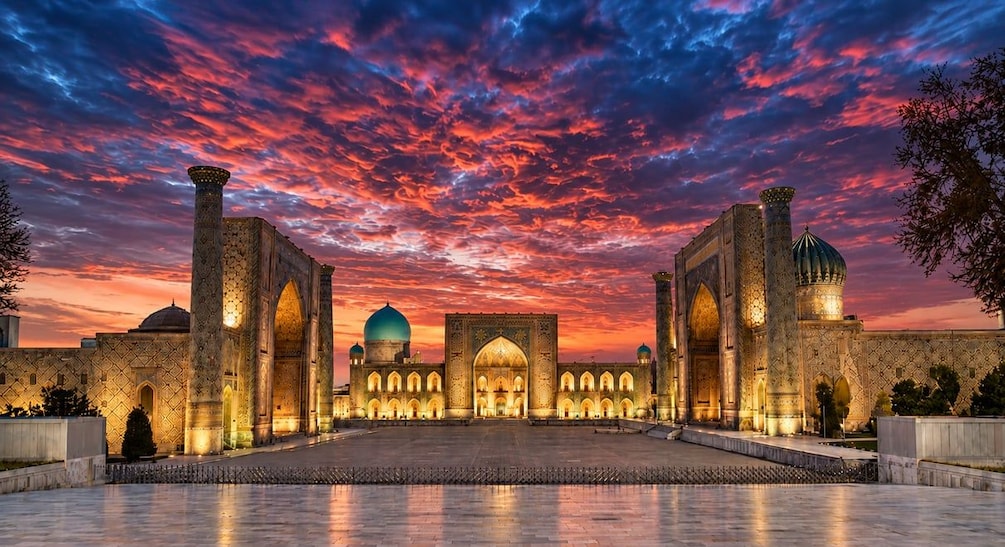 A historic building with intricate architecture, a large dome, and a courtyard at sunset. 1