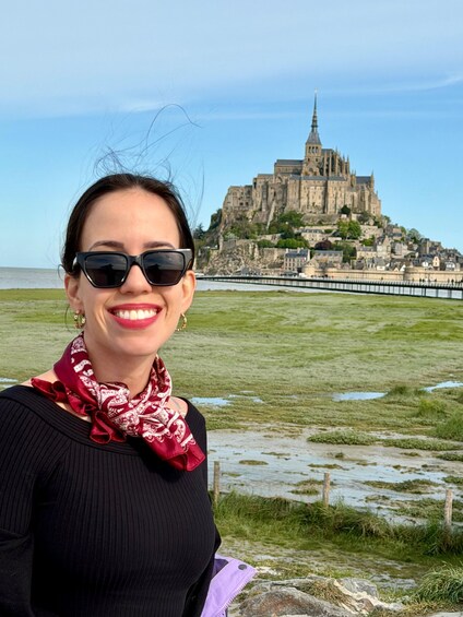 A person standing in a grassy area with a historic castle in the background. 5