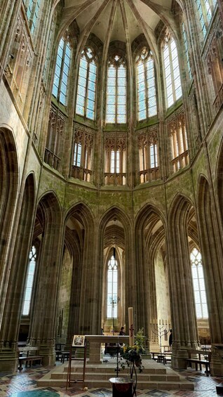 A cathedral interior with high vaulted ceilings, large stained glass windows, and a central altar. 2