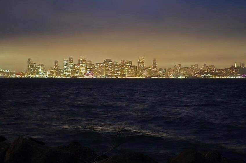 A city skyline at dusk with illuminated buildings across a body of water. 4