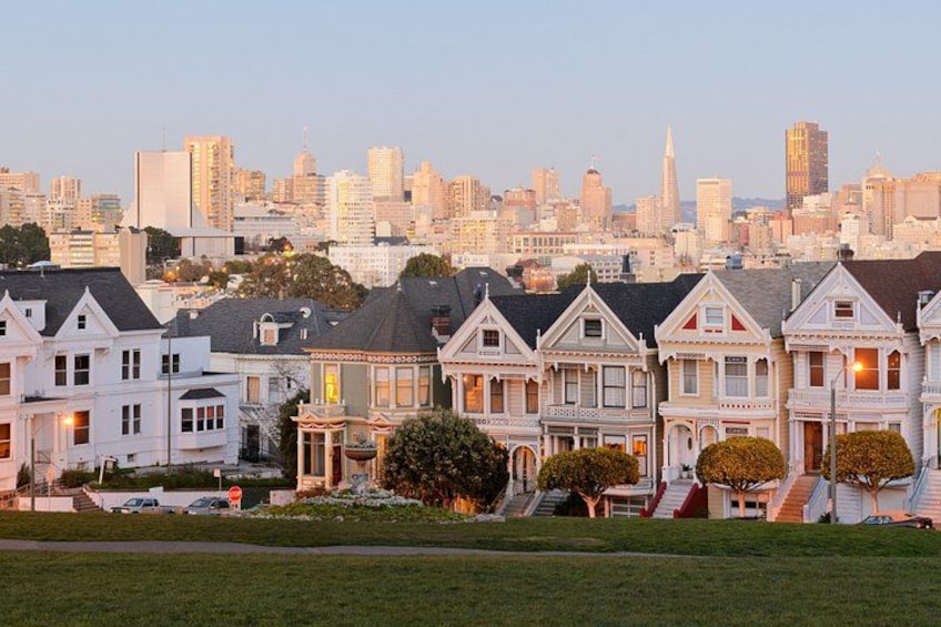 Una hilera de casas victorianas con el horizonte de la ciudad al fondo. 4