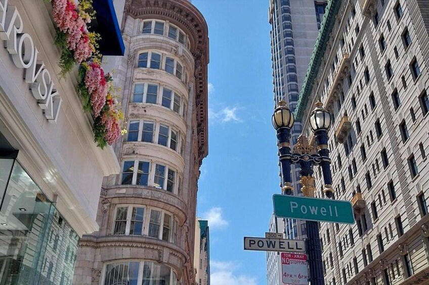 A street view with Powell Street sign, a building with a curved facade, and a street lamp. 3