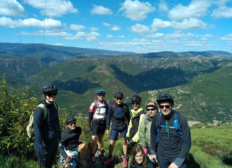 A group of cyclists on a mountain trail with a scenic view of valleys and mountains. 4