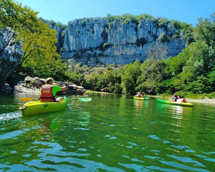 People kayaking on a river surrounded by cliffs and greenery. 5