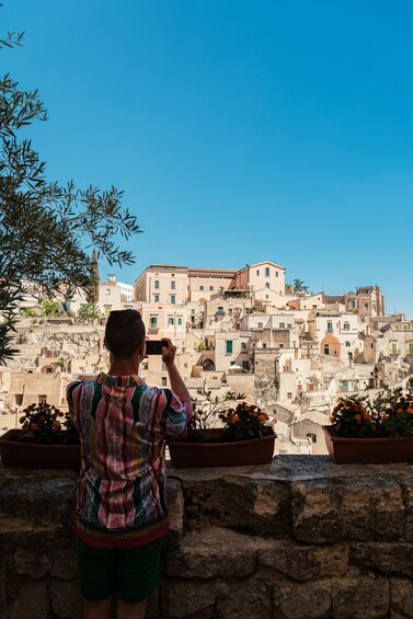A person taking a photo of a historic town with terracotta buildings. 5