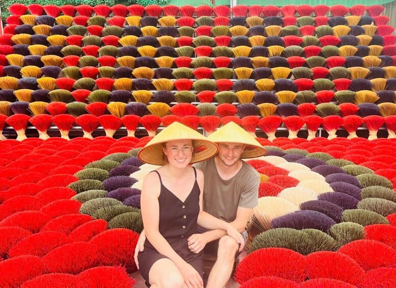 A woman and a man sitting in the center of a large, colorful flower arrangement. 5