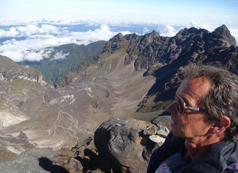 A mountainous landscape with rocky terrain and a person standing on a ridge. 1