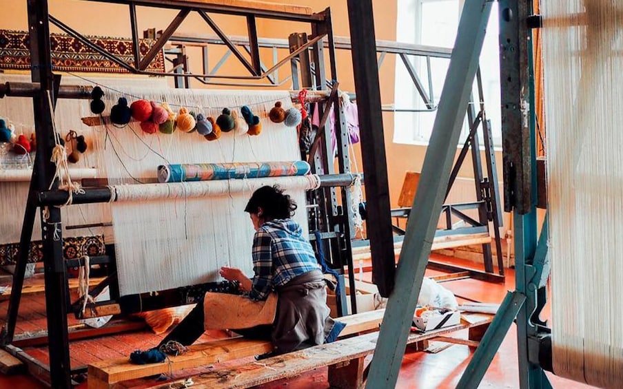 A person weaving on a loom with colorful yarns. 4