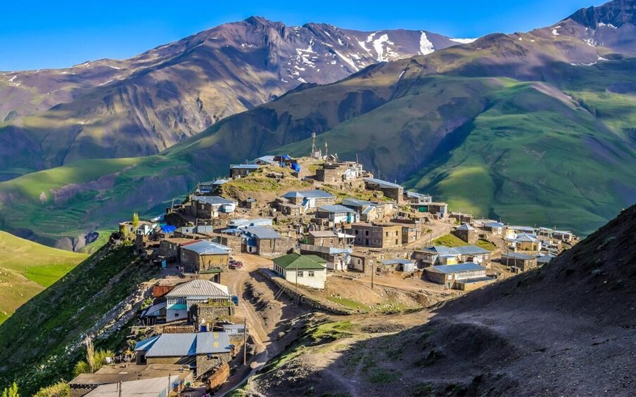 A mountainous village with buildings and a prominent church on a hill. 1
