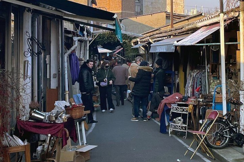 A narrow street with shops on either side, bicycles parked outside, and people browsing. 3