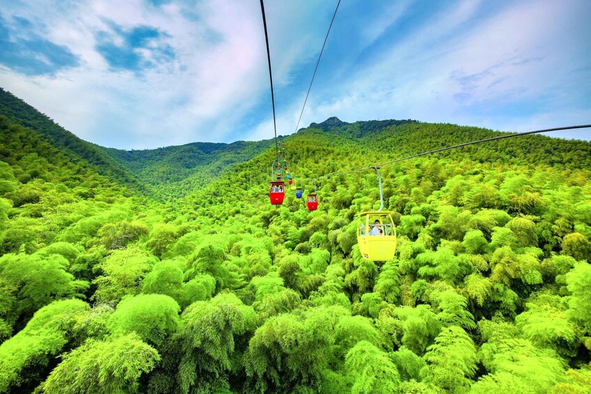 A cable car system in a lush green forested area with hills in the background. 3