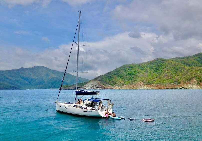 A sailboat on calm waters with a mountainous backdrop. 1