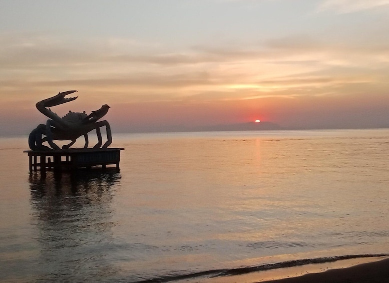 A sculpture of a crab on a pier with a sunset in the background. 5