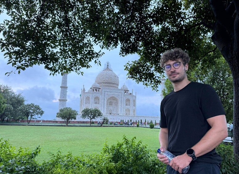 Henkilö seisoo Taj Mahalin edessä, ja kuvan etualalla on puu. 2