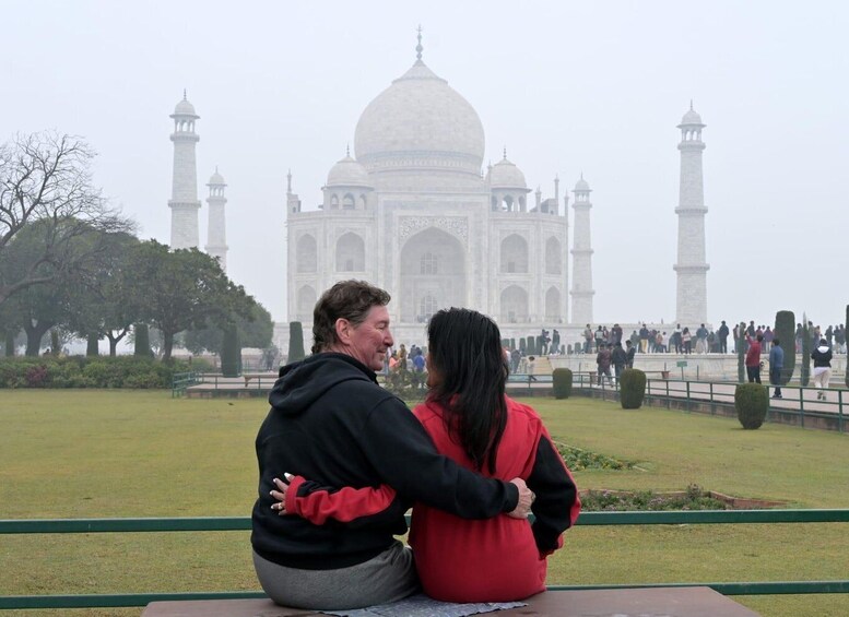 A couple sitting on a bench facing the Taj Mahal. 3