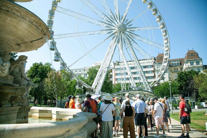 A Ferris wheel, a fountain, and people in a park. 3
