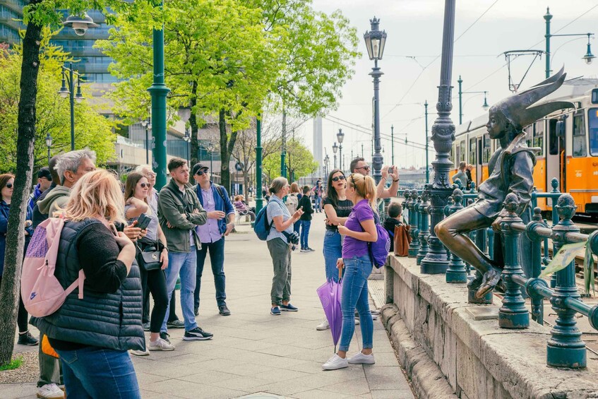 A busy urban street with people walking and a statue of a figure with a large hat. 2