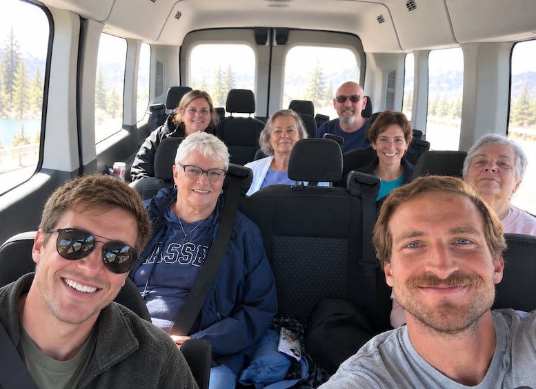A group of people seated inside a vehicle with a scenic view of trees and mountains through the windows. 4