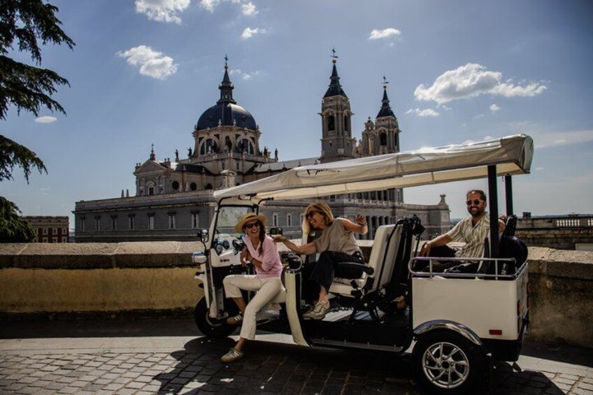 A group of people on a golf cart in front of a historic building with domes and towers. 3