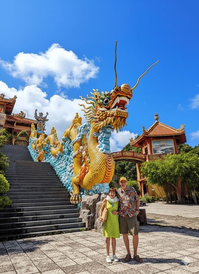 Une grande sculpture de dragon orne un escalier, et on aperçoit un temple ainsi que deux personnes debout devant. 1
