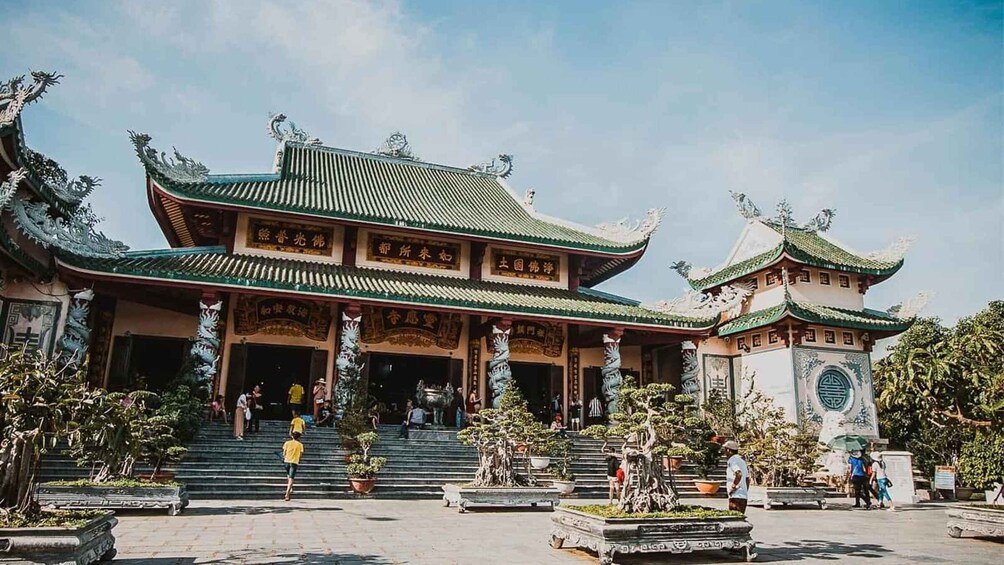 Un bâtiment traditionnel chinois, doté de toits et de colonnes richement décorés, entouré de jardins bien entretenus et de visiteurs. 3