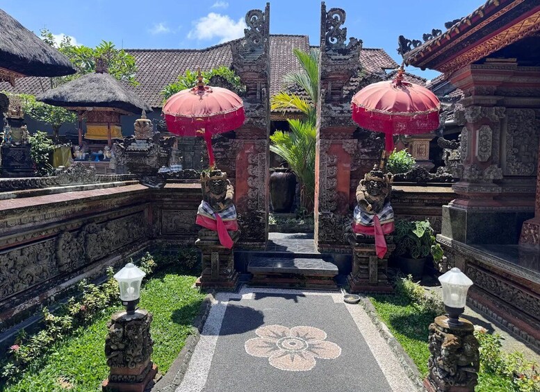 A temple courtyard with stone statues, red umbrellas, and a floral pavement. 5