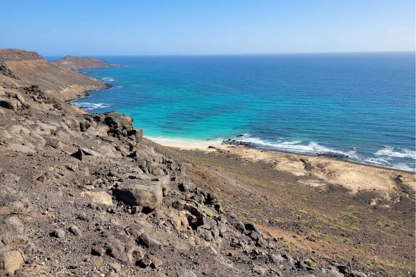 A coastal landscape with rocky terrain and a beach. 5