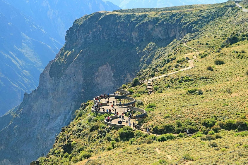A winding mountain road with a stone amphitheater and a steep cliff. 4