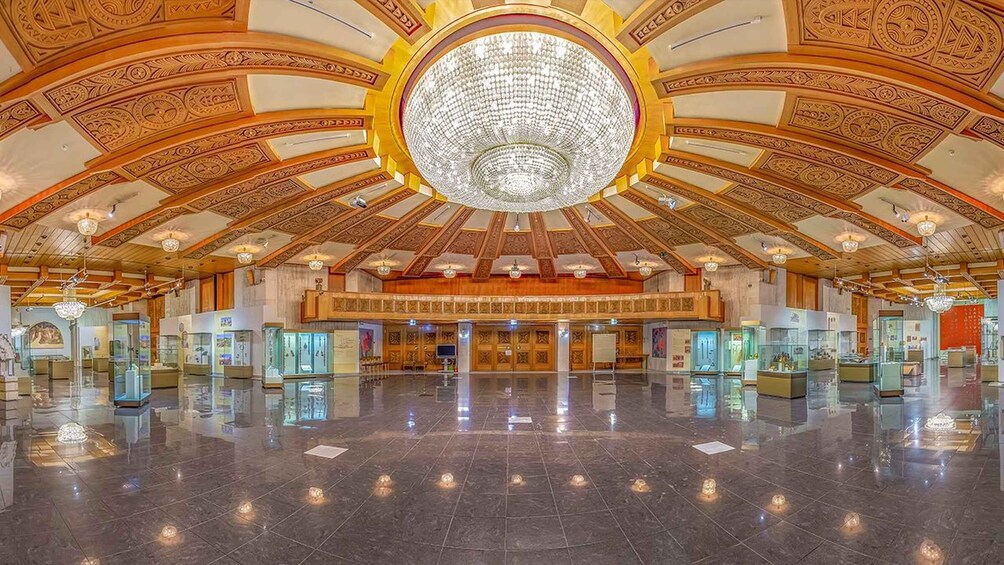 A grand lobby with a large chandelier, ornate ceiling, and glass display cases. 5