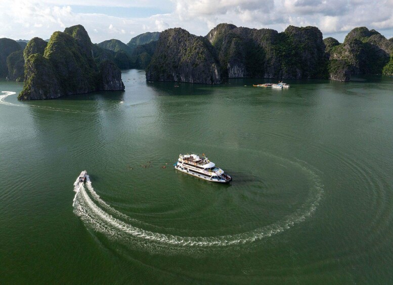 A large boat moving through calm waters surrounded by limestone karsts. 2